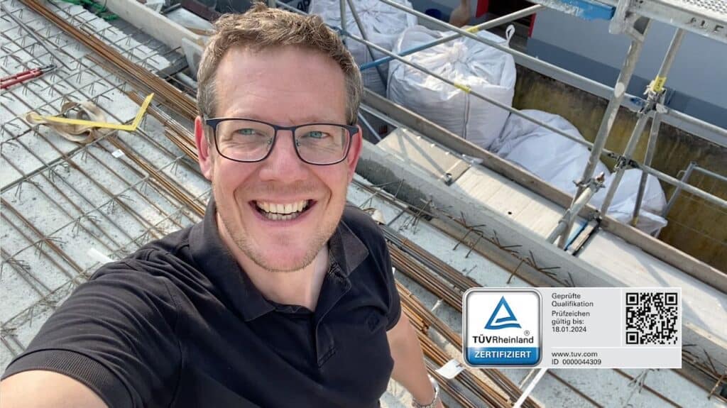 Baugutachter Carsten Nessler mit TÜV-Zertifikat auf dem Dach eines Neubaus